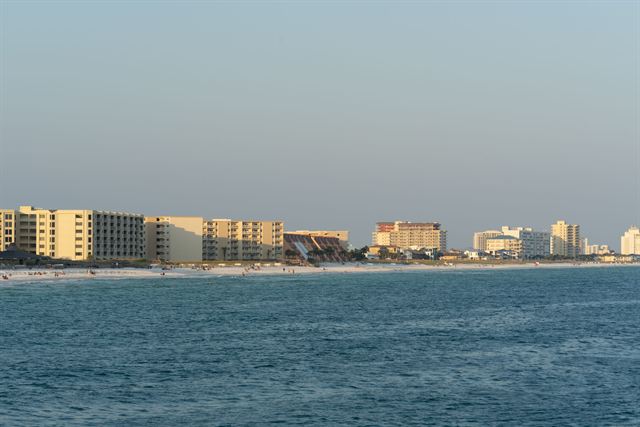 Row of Destin beachfront condos and resorts along the Gulf shore at dusk across calm water