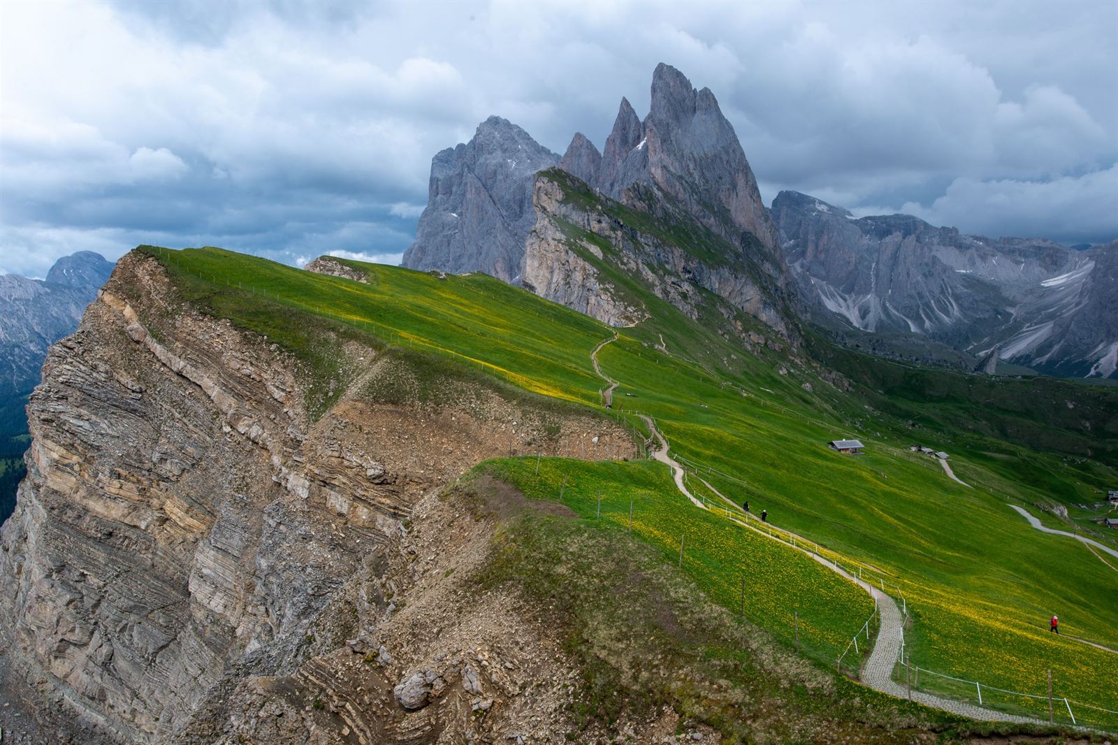 Seceda ridge in the Dolomites, a green meadow tilting up to jagged rock pinnacles above a sheer cliff