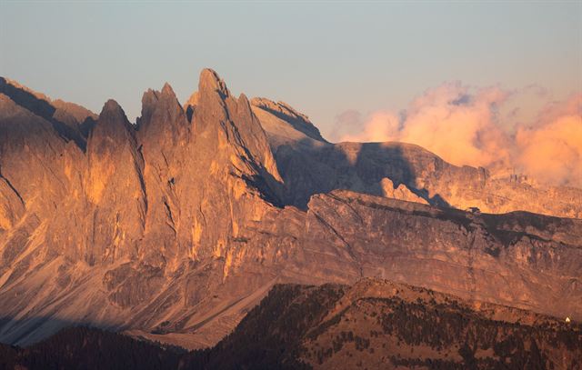 Jagged Seceda and Odle peaks of the Dolomites glowing orange at summer sunset