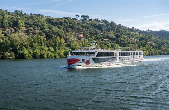 River cruise ship sailing along the Douro between wooded hills in Portugal