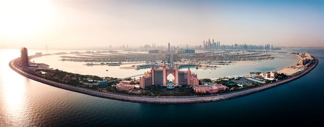 Aerial view of Palm Jumeirah with Atlantis hotel on the crescent and Dubai Marina skyline behind