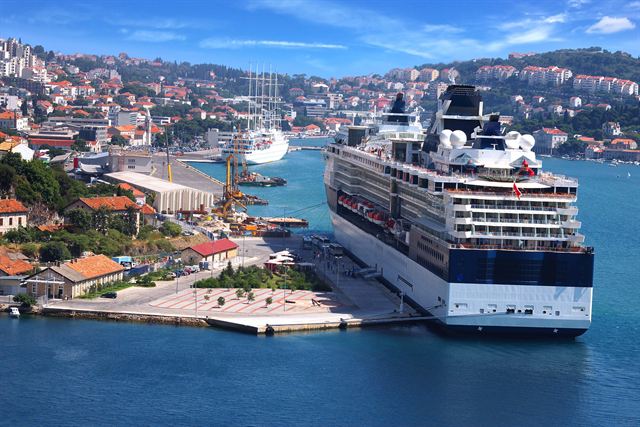 Cruise ship docked at Gruz port in Dubrovnik with hillside houses behind