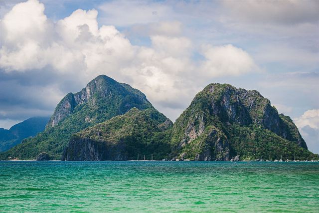 Twin limestone karst islands above turquoise shallows in El Nido, Palawan