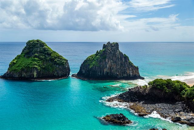 The twin Morro Dois Irmaos rocks rising from turquoise water in Fernando de Noronha, Brazil