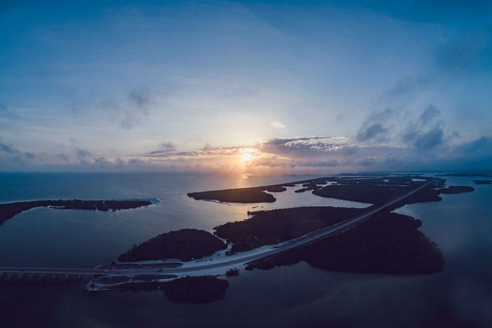 Aerial view at sunset over Fort Myers Beach with mangrove islands and a causeway crossing Estero Bay
