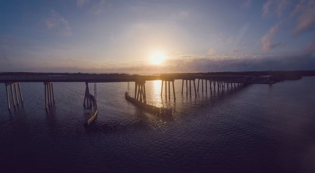 Bridge silhouetted against the setting sun over calm water at Fort Myers Beach, Florida