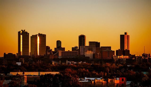 Fort Worth downtown skyline silhouetted against a glowing orange sunset sky
