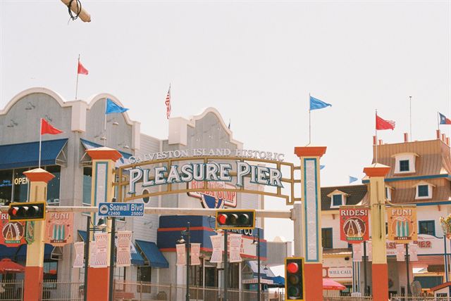 Colorful entrance arch of the Galveston Island Historic Pleasure Pier on Seawall Boulevard with flags