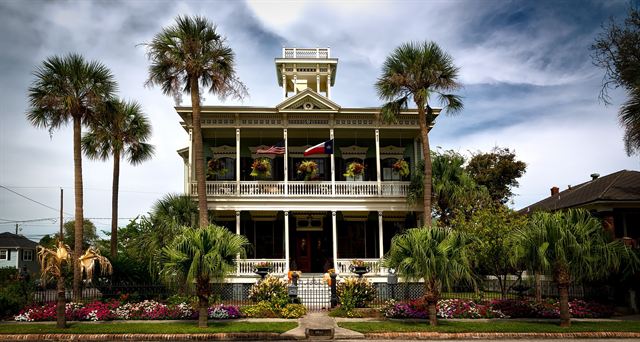 Historic Victorian house with wraparound porches, palm trees and flower gardens in Galveston, Texas