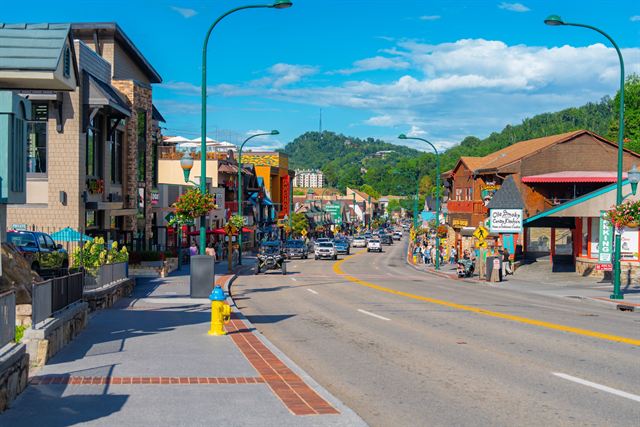 The Parkway in downtown Gatlinburg with shops, flower-hung lampposts and forested Smoky Mountain hills