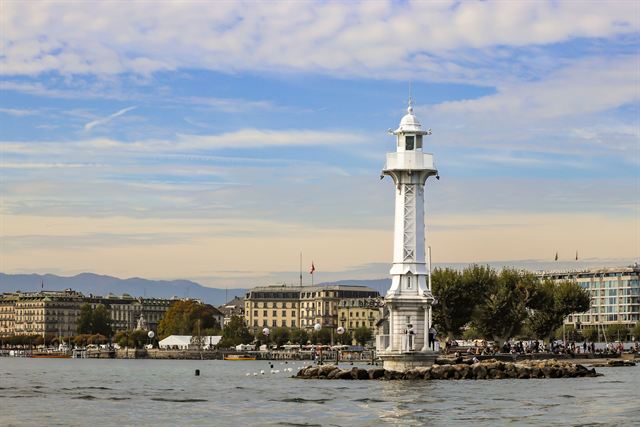 Bains des Pâquis lighthouse on its jetty in Lake Geneva with lakefront buildings behind