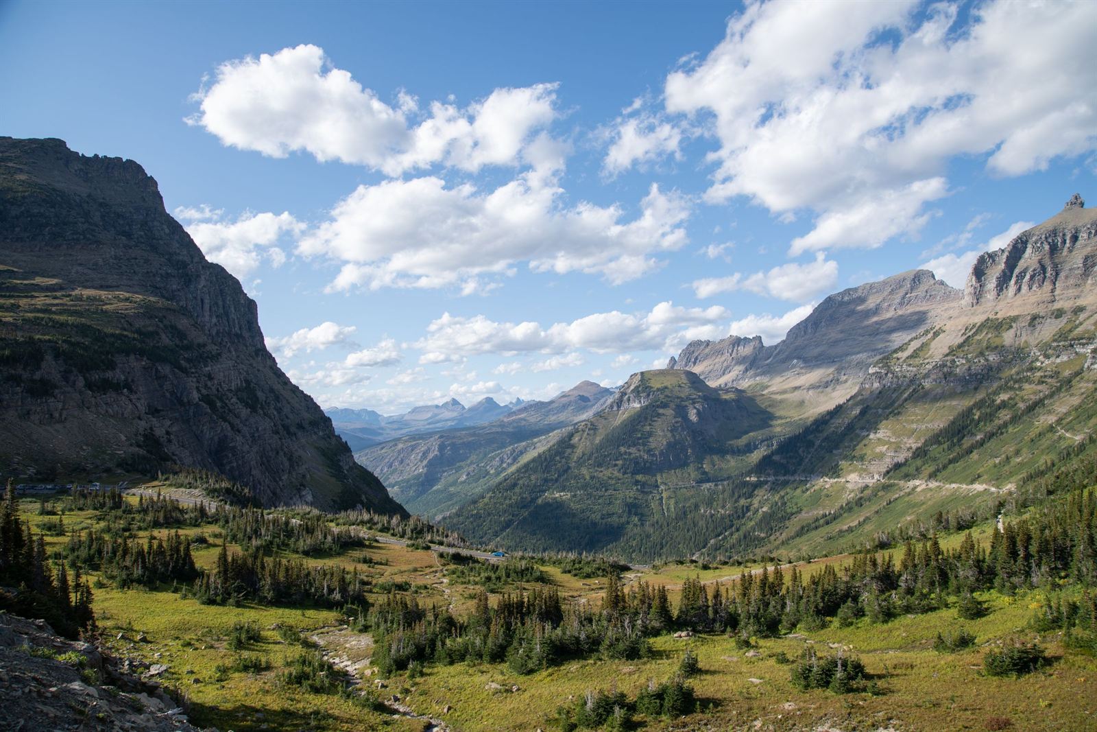 Glacier National Park valley along Going-to-the-Sun Road country with rugged peaks and green meadows under clouds
