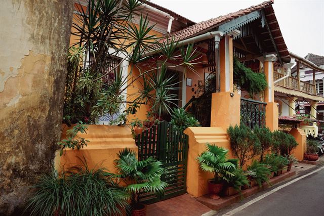 Ochre Portuguese-era heritage house with tiled roof, balcony and potted palms in Panaji's Fontainhas, Goa