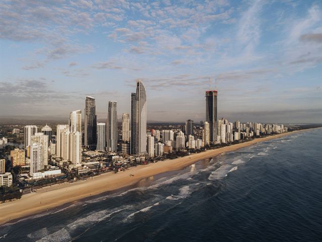 Surfers Paradise high-rise skyline lining the Gold Coast beach at sunrise, aerial view