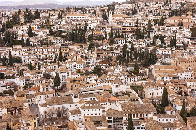 Dense whitewashed houses and cypress trees of Granada's hillside Albaicín quarter