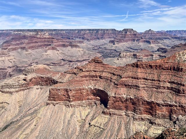 Striped red rock layers and eroded ridges of the Grand Canyon below the rim on a bright day