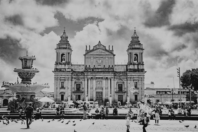 Black-and-white view of the twin-towered Metropolitan Cathedral and fountain on Plaza de la Constitucion, Guatemala City