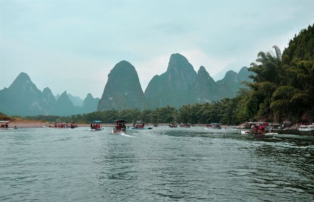 Bamboo rafts on the Li River at Yangshuo beneath misty karst mountains and palms