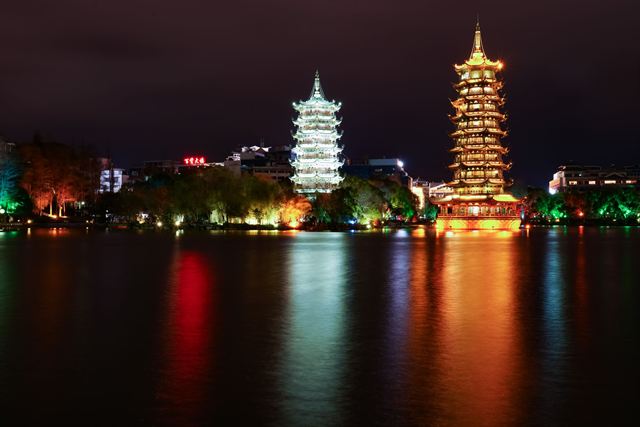 Illuminated Sun and Moon Pagodas reflected in Shan Lake in Guilin at night