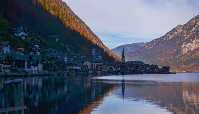 Hallstatt lakeside houses and church reflected in calm Hallstätter See under steep slopes