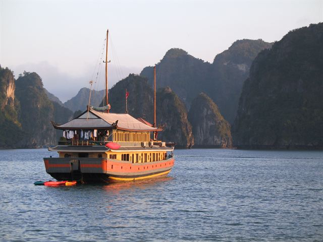 Traditional junk boat in front of misty karst cliffs
