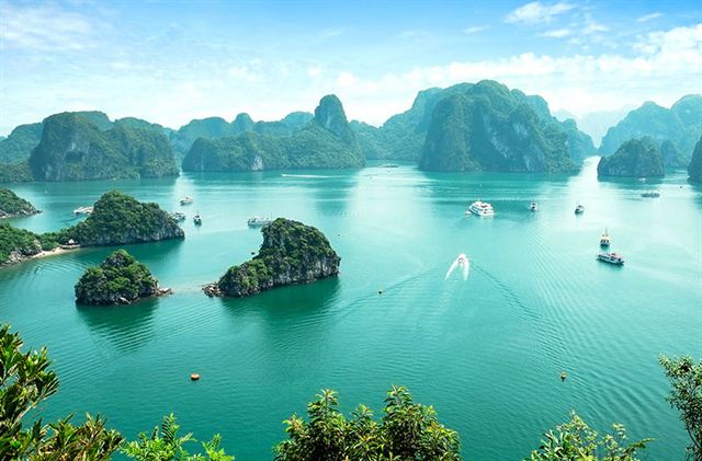 Halong Bay from a hilltop, emerald water dotted with boats and forested limestone karst islands