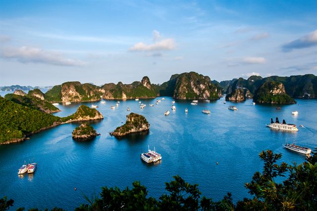 View over Halong Bay with cruise boats weaving between steep limestone karst islets, Vietnam