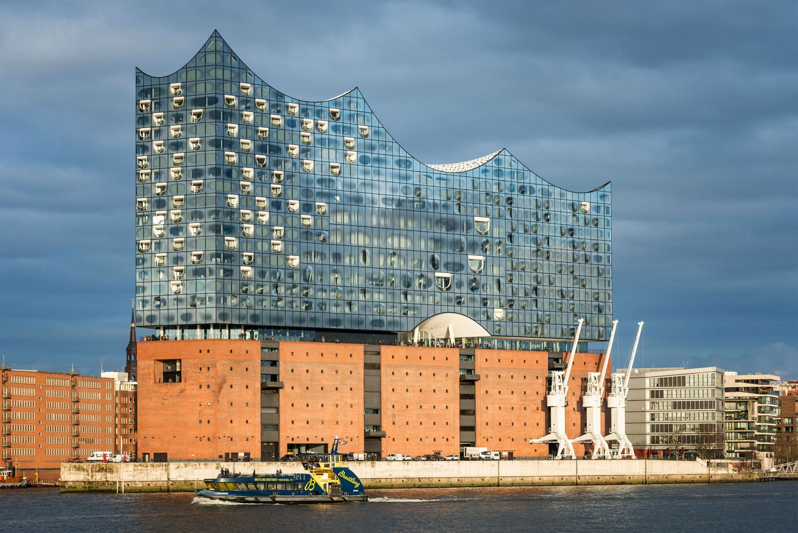 Elbphilharmonie concert hall's wave-shaped glass top on a red-brick warehouse beside the Elbe in Hamburg