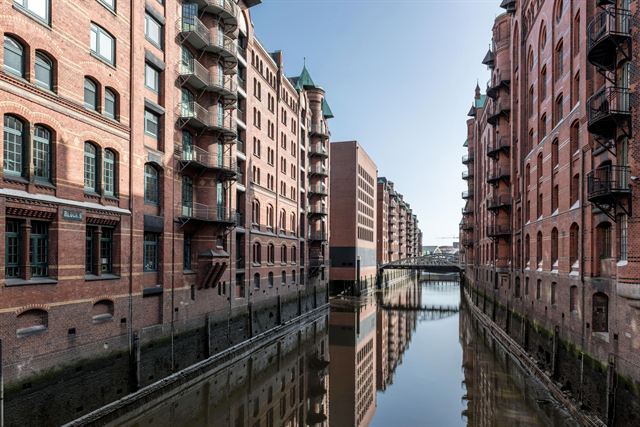 Speicherstadt red-brick warehouses lining a narrow canal in Hamburg, reflected in still water