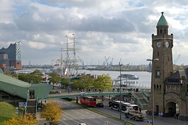 St. Pauli Landungsbrücken clock tower in Hamburg with harbor, tall ship and Elbphilharmonie in view