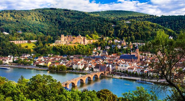 Heidelberg old town on the Neckar River with the Old Bridge and castle ruins on forested hills