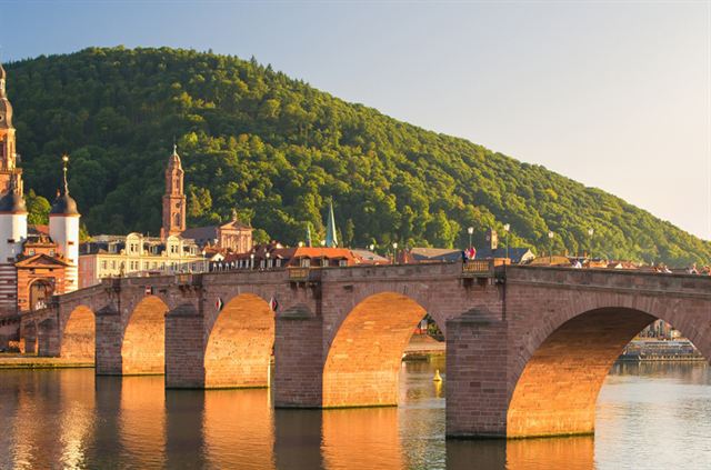 Arches of the Old Bridge in Heidelberg glowing at sunset with the town gate towers behind