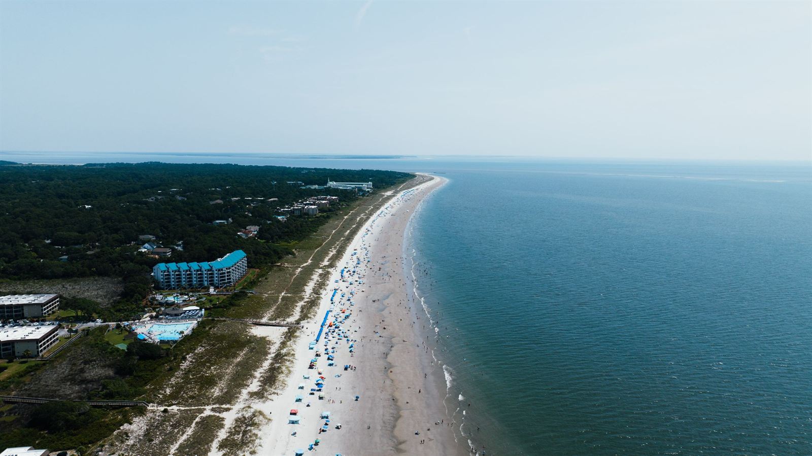 Aerial view of Hilton Head Island's long beach with resort buildings, umbrellas and the Atlantic