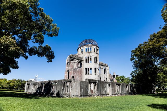 Hiroshima's Atomic Bomb Dome (Genbaku Dome) ruin on green lawn under deep blue sky