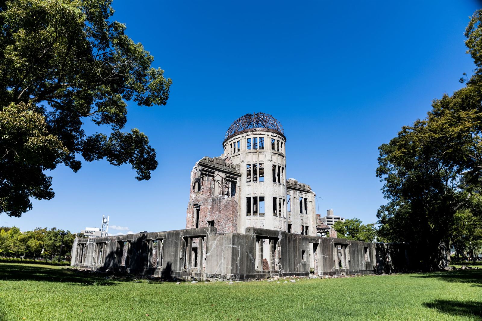 Hiroshima's Atomic Bomb Dome (Genbaku Dome) ruin on green lawn under deep blue sky