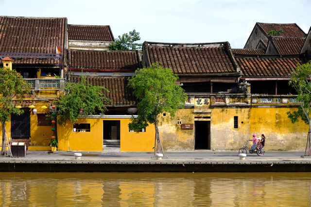 Mustard-yellow shophouses with tiled roofs along the Thu Bon riverfront in Hoi An Ancient Town