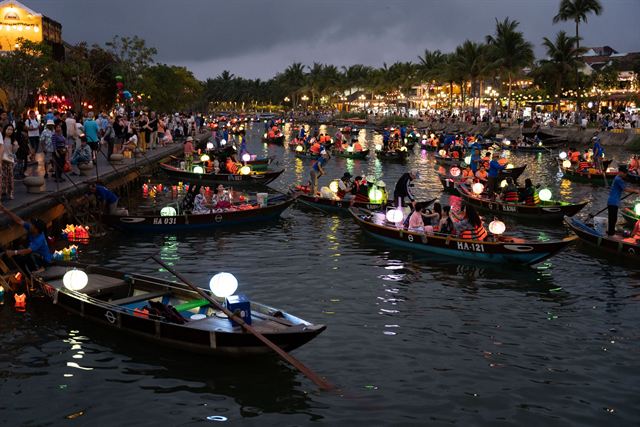 Hoi An Ancient Town riverside at dusk with lantern-lit boats on the Thu Bon River and crowds on the quay