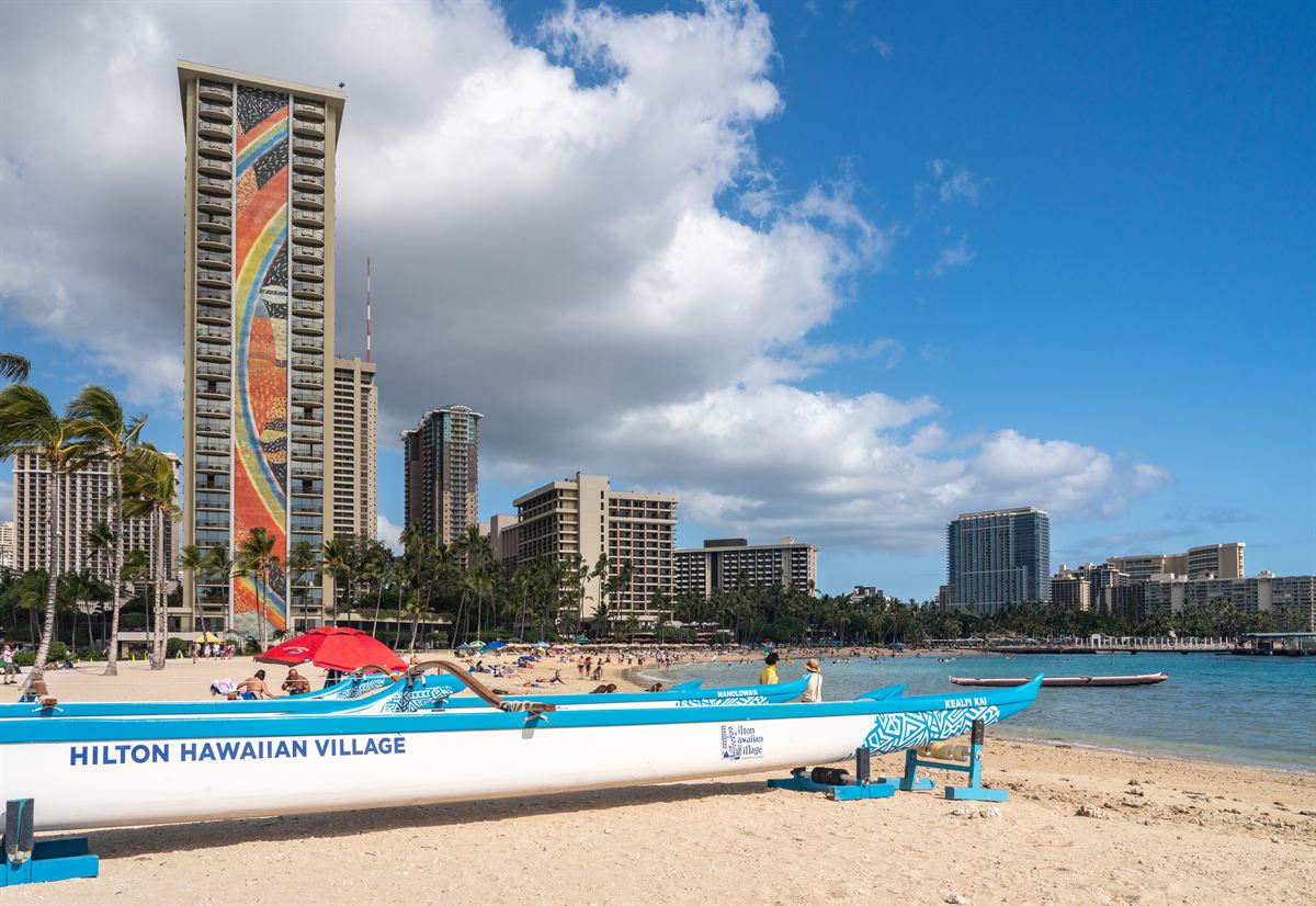 Hilton Hawaiian Village outrigger canoe on the beach below the mosaic Rainbow Tower, Waikiki
