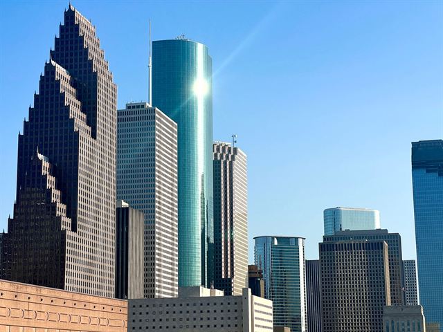 Glass and granite skyscrapers of downtown Houston against a clear blue sky