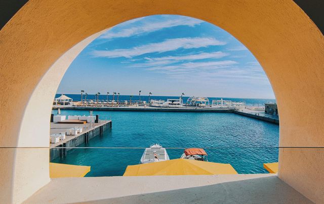 Hurghada marina with white boats and turquoise Red Sea water framed by a yellow archway