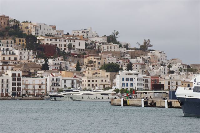 Whitewashed houses of Ibiza old town climbing the hillside above the marina and moored yachts
