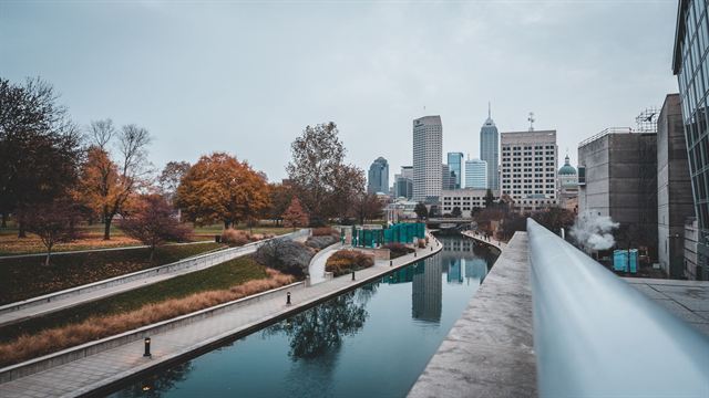 Indianapolis Central Canal walkway with autumn trees and the downtown skyline reflected in the water