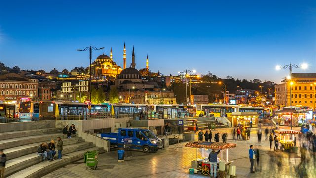 Suleymaniye Mosque lit up at dusk above the Eminonu waterfront square in Istanbul