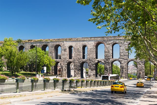 Roman-era Aqueduct of Valens arches spanning a busy Istanbul street with yellow taxis