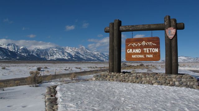 Grand Teton National Park entrance sign with the Teton Range beyond snowy flats