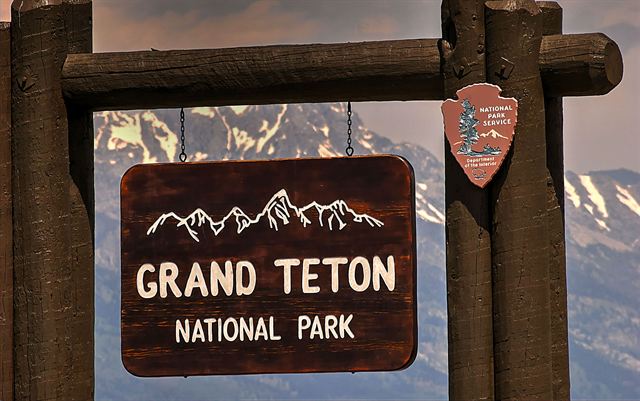Wooden Grand Teton National Park sign with mountains behind