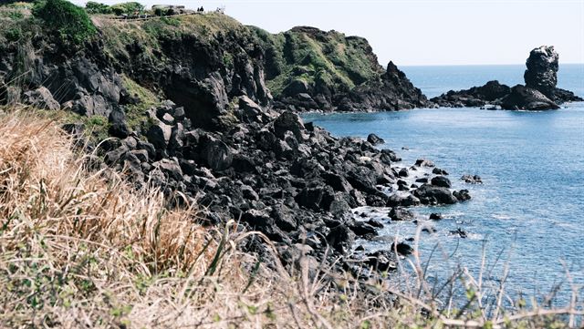 Jeju's black volcanic rock coastline with the Oedolgae sea stack rising offshore