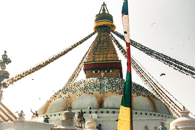 White dome and gilded tower of Boudhanath Stupa strung with colorful prayer flags in Kathmandu