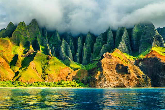 Jagged green Na Pali Coast cliffs rising from the sea on Kauai