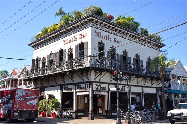 Historic white building with balconies housing the Whistle Bar on Duval Street, Key West